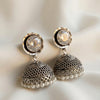 Pair of silver earrings with crystal and pearl details on a soft background