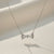 Luna Knot Necklace by Evvara Vogue featuring a delicate bow-shaped crystal pendant on a gold-tone chain