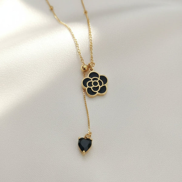 Black floral pendant necklace with gold chain and dangling heart charm by Evvara Vogue