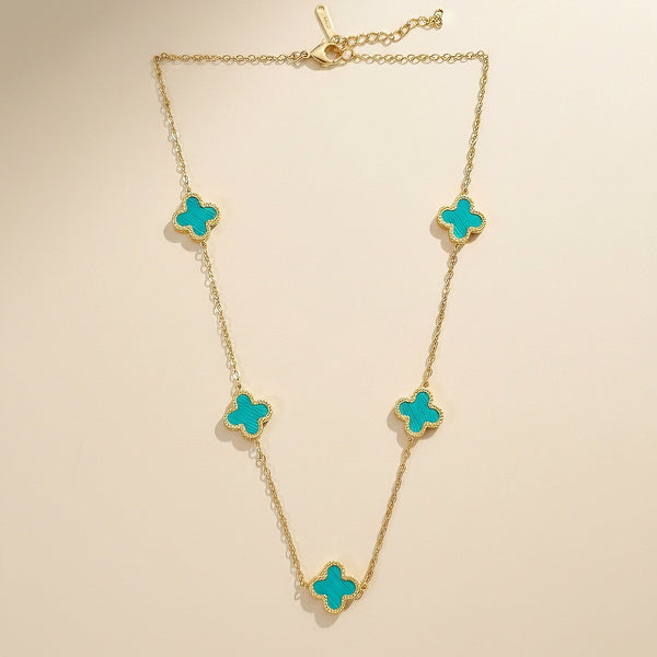 Close-up of turquoise clover detailing on gold stainless steel necklace by Evvara Vogue