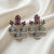 Ornate silver earrings with red gemstones on a white fabric background