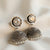 Pair of silver earrings with crystal and pearl details on a soft background