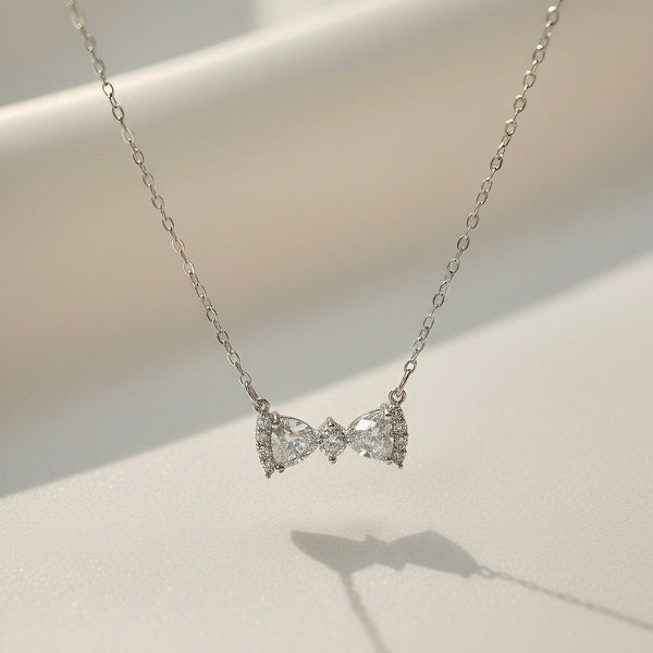 Luna Knot Necklace by Evvara Vogue featuring a delicate bow-shaped crystal pendant on a gold-tone chain