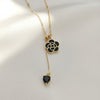 Black floral pendant necklace with gold chain and dangling heart charm by Evvara Vogue