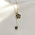 Black floral pendant necklace with gold chain and dangling heart charm by Evvara Vogue