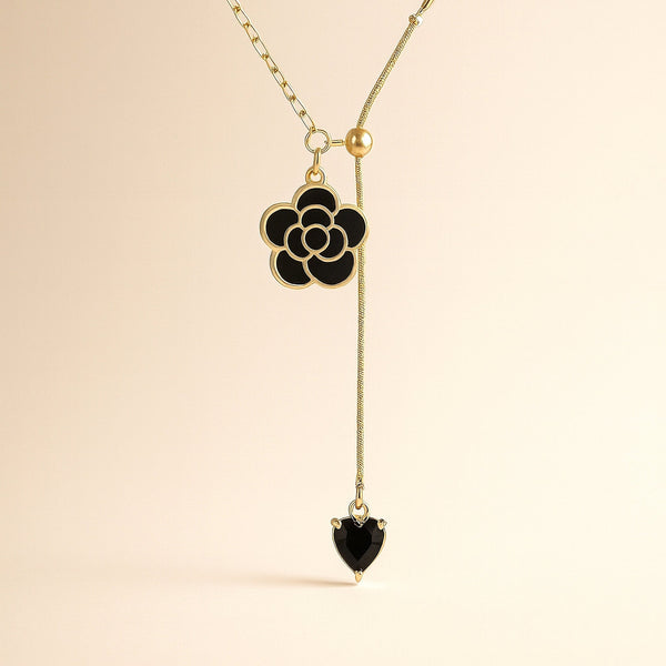 Minimal black flower necklace with gold finish styled on soft satin background