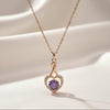 Rose gold heart pendant necklace with violet center stone on soft satin background