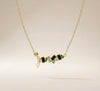Minimal modern gold necklace with gemstone bar and pearl drop on satin background