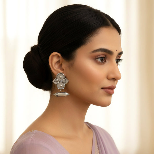 Woman wearing silver earrings with a plain background