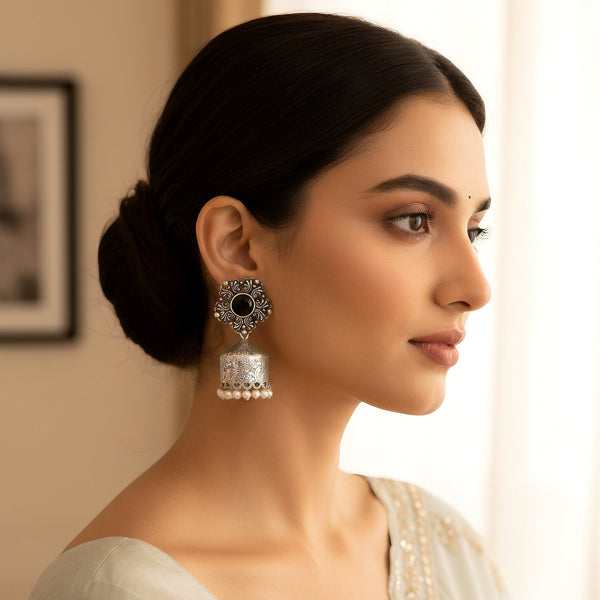 Woman wearing a silver earring with a black center, looking to the side.