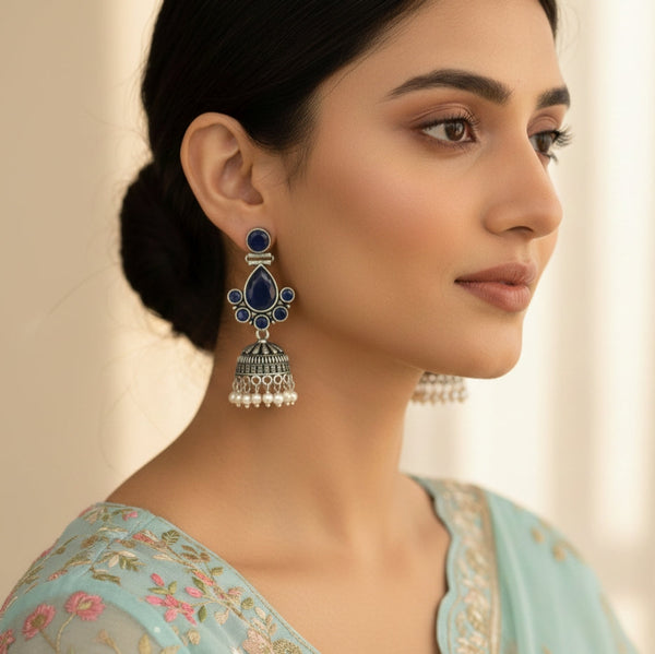 Woman wearing a blue and silver earring with a neutral background