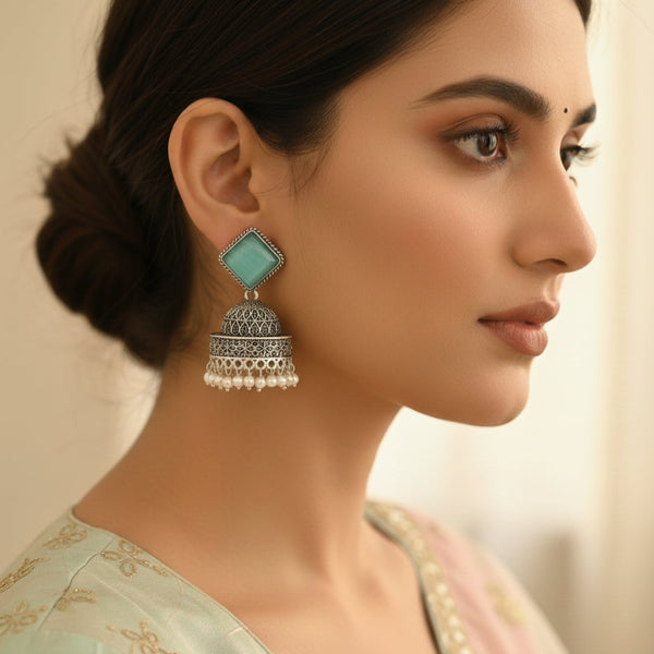 Close-up of a woman wearing a turquoise earring with intricate design.
