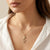 Serpent Glow gold-tone anti-tarnish stainless steel necklace by Evvara Vogue on soft satin background