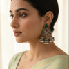Woman wearing intricate earrings with a neutral background